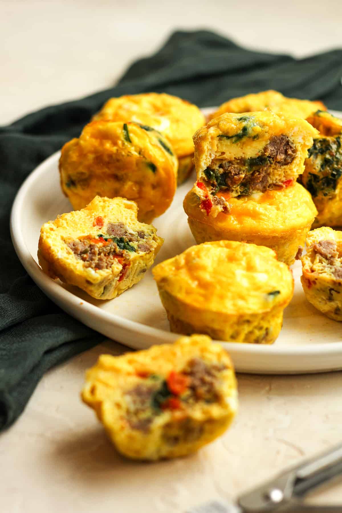 Side view of a plate of sausage egg and cheese muffins with some split in half.
