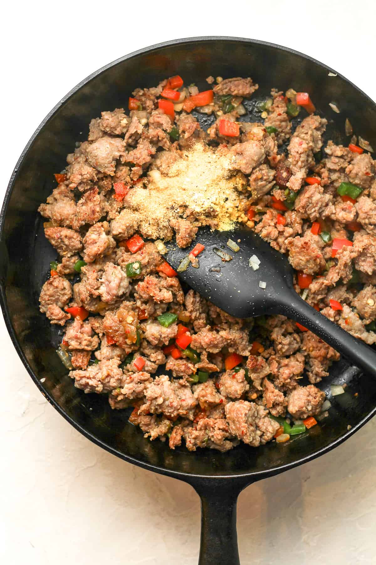 A skillet of the browned sausage with seasonings.