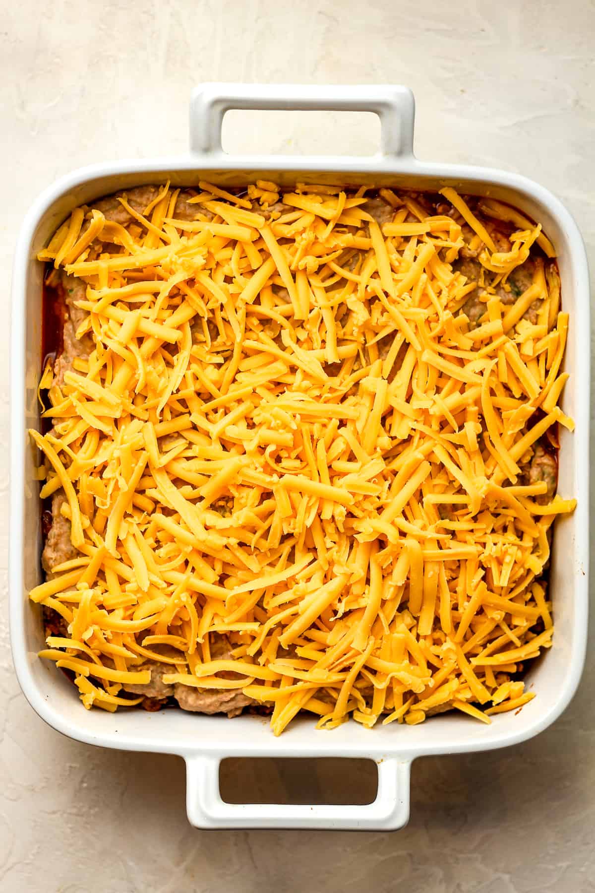 A dish of the casserole with shredded cheese.