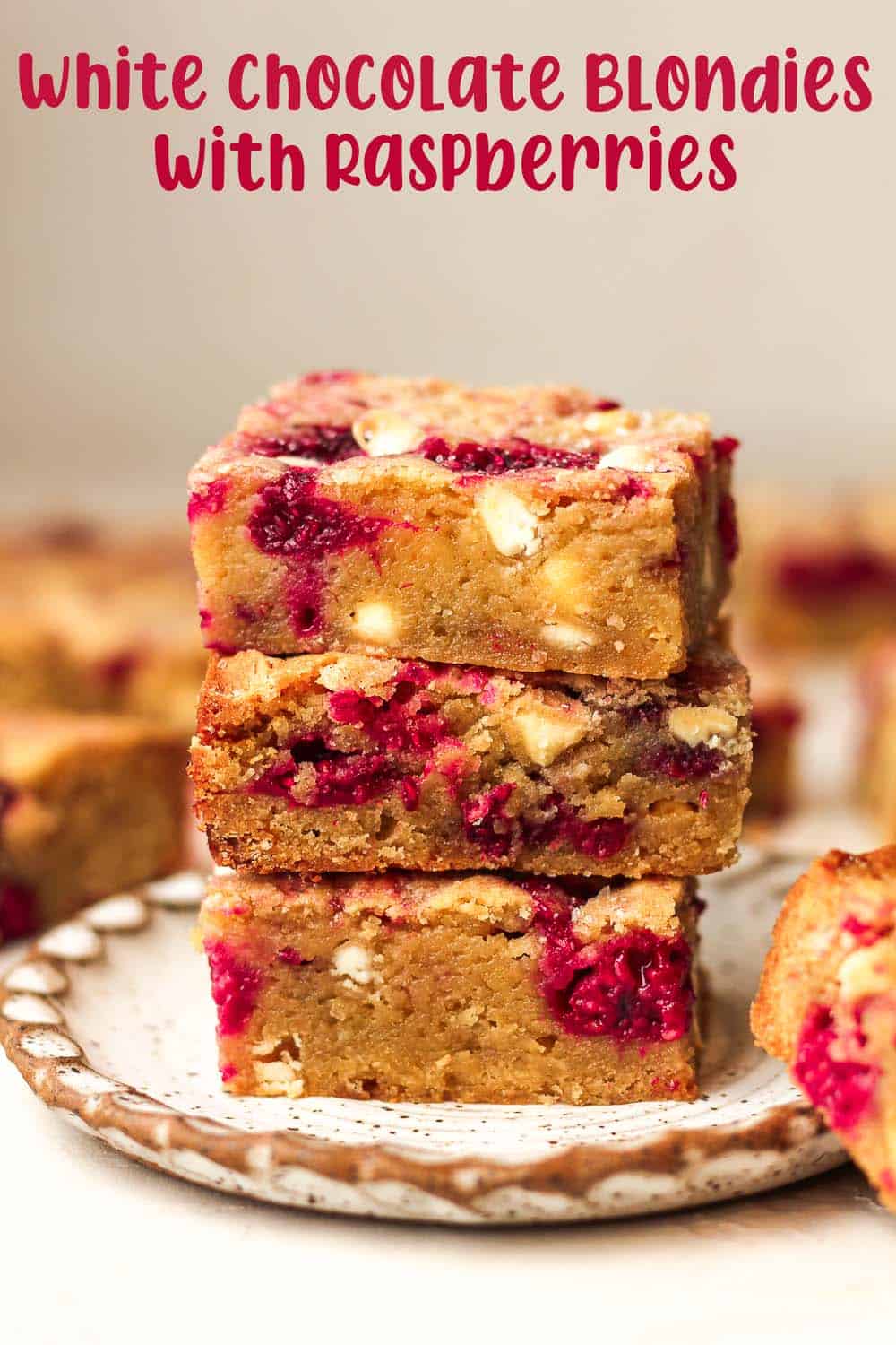 Side view of a stack of three white chocolate blondies with raspberries.