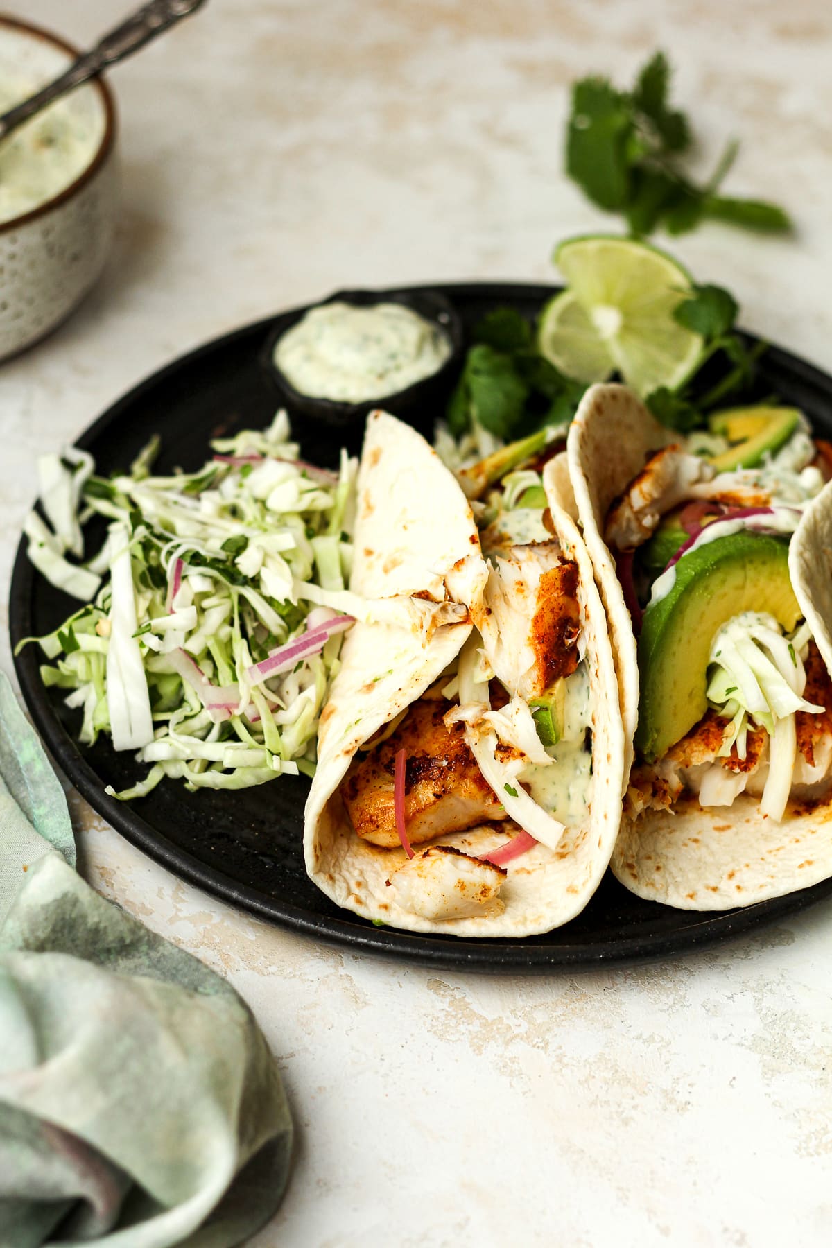 Side view of two fish tacos on a plate.