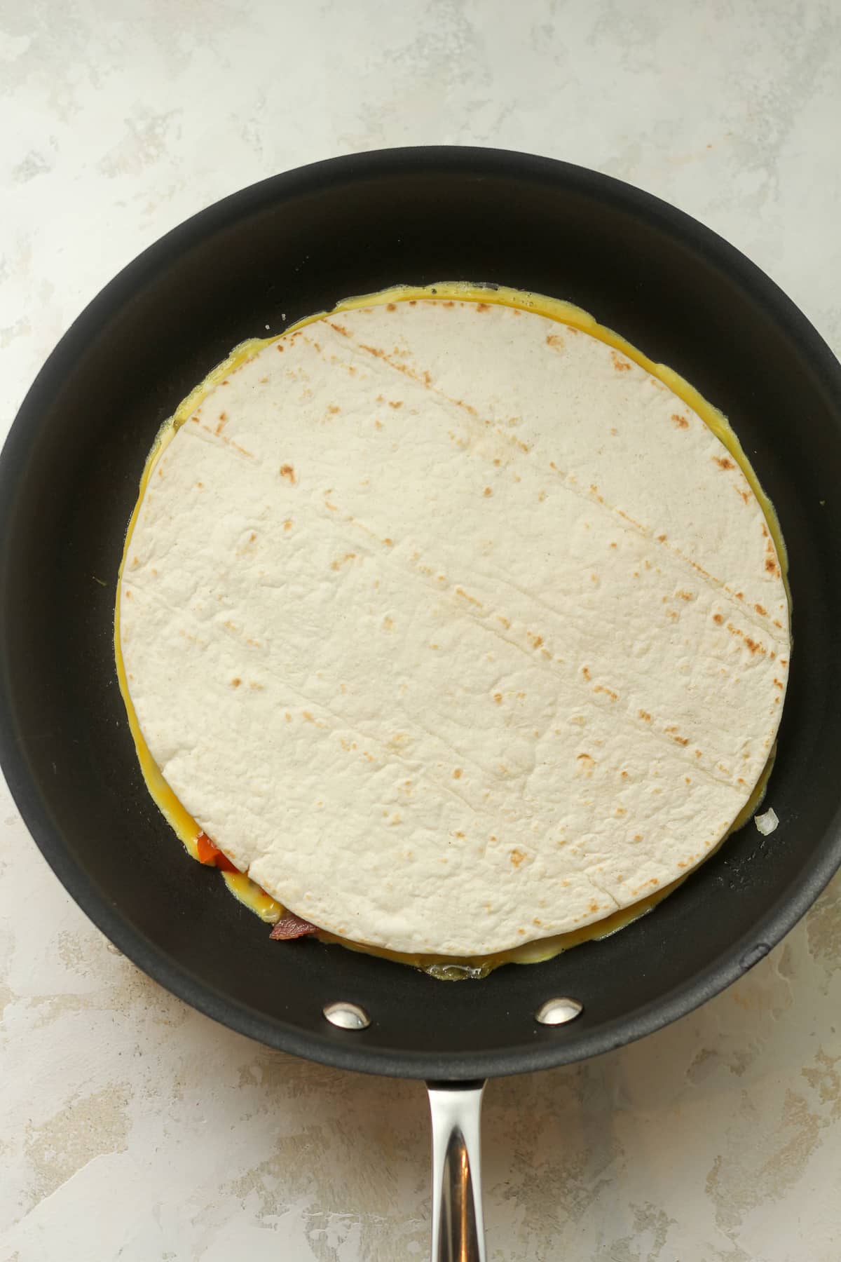 A pan of the egg mixture with a tortilla on top.