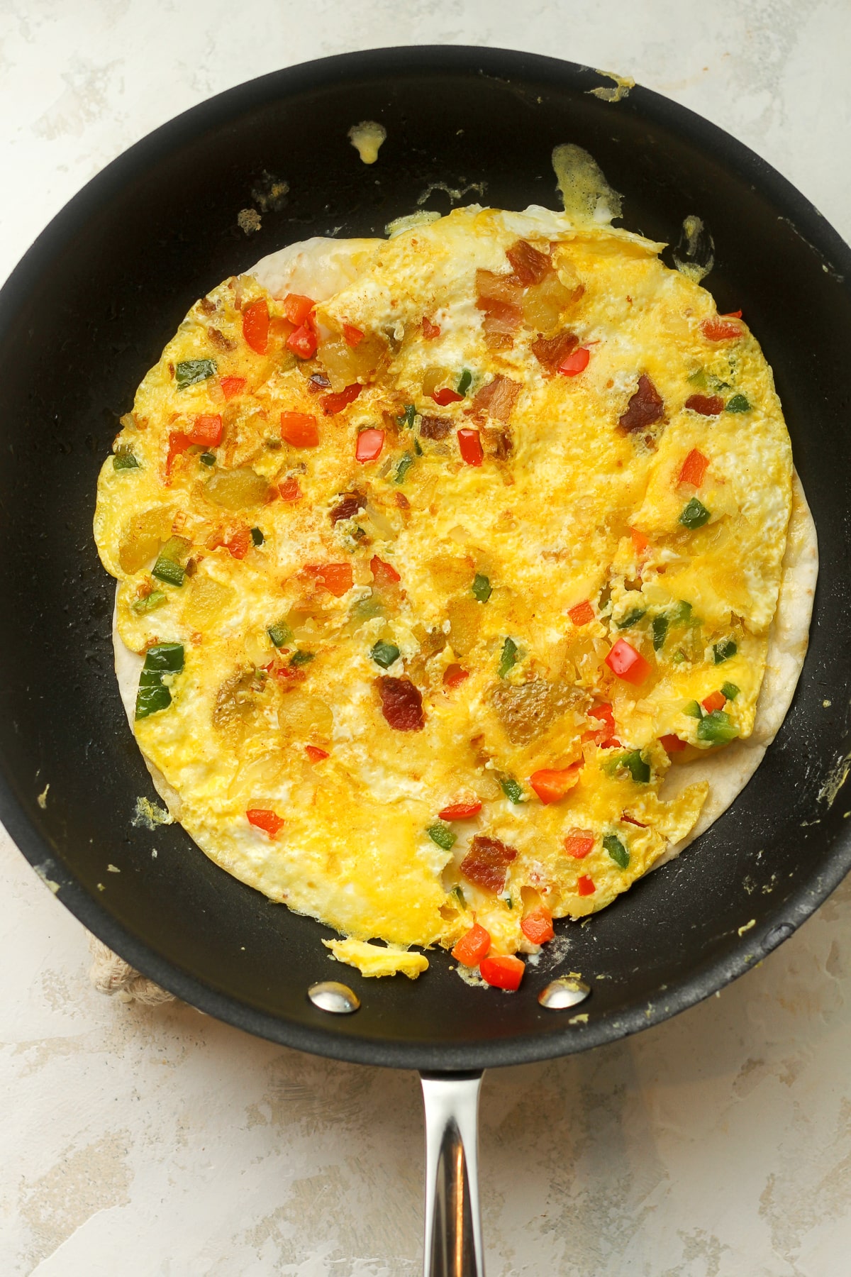 A nonstick pan with a tortilla and egg and veggie mixture.