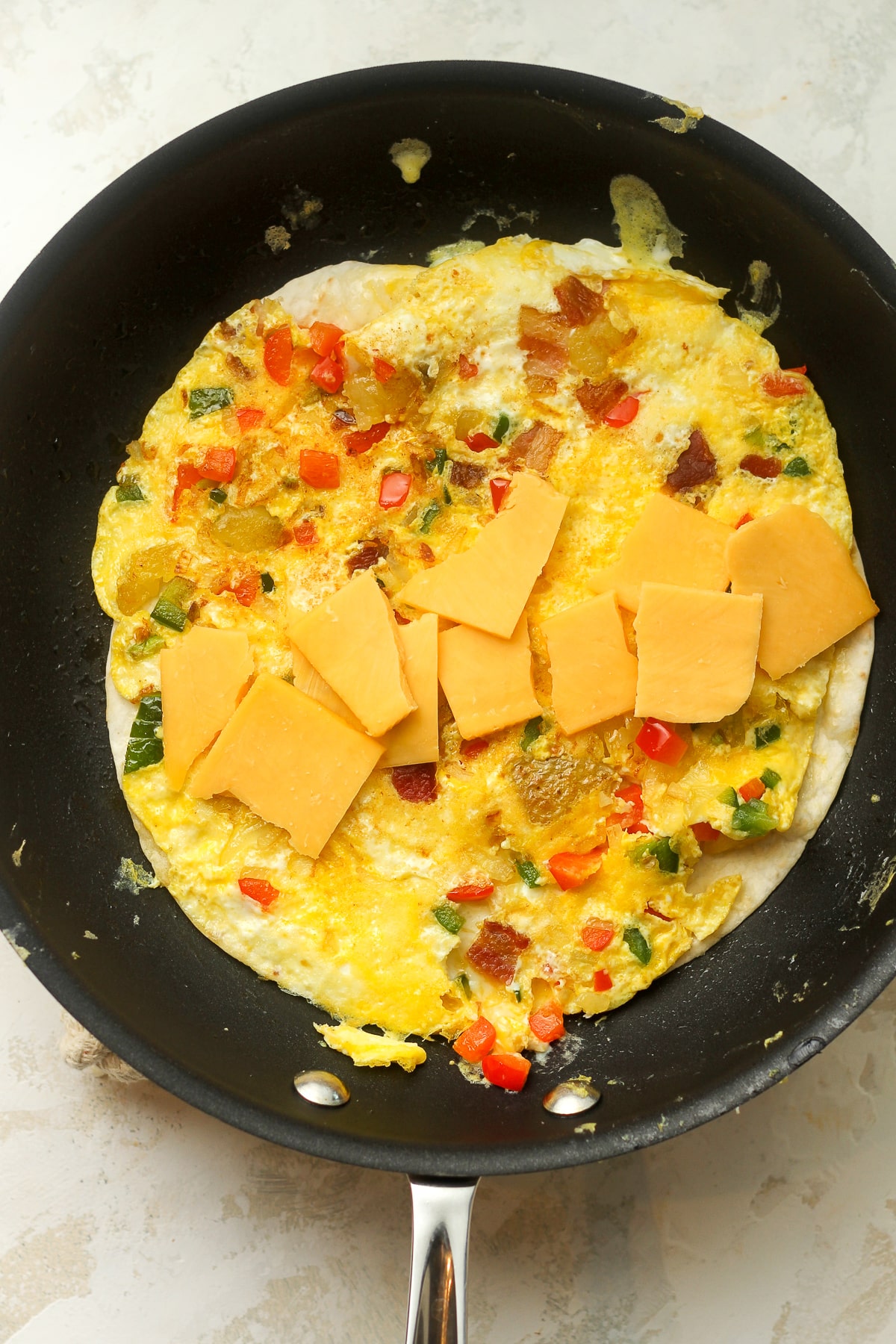 A nonstick pan with a tortilla, egg mixture and cheese.