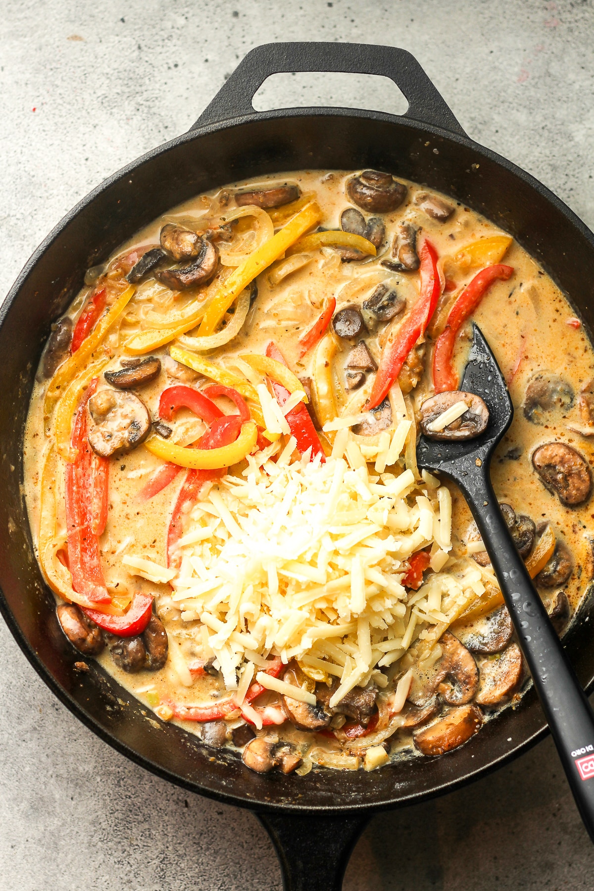 A skillet of the creamy sauce and veggies plus parmesan cheese on top.