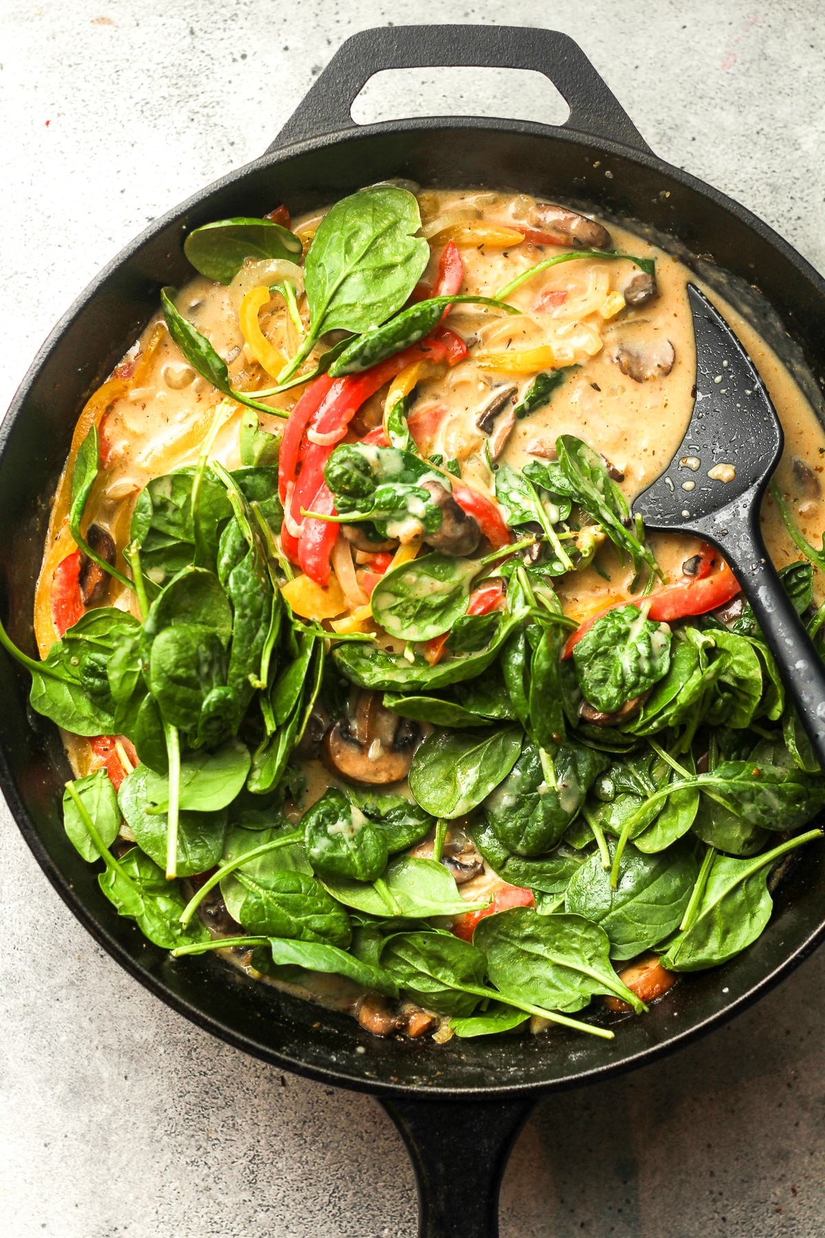 A skillet of the sauce after adding baby spinach.