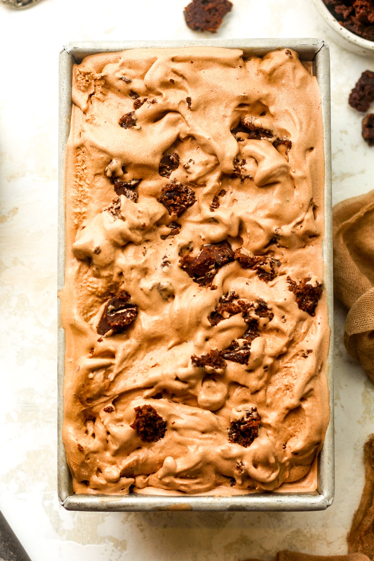 A closeup on a loaf pan of chocolate fudge brownie ice cream.