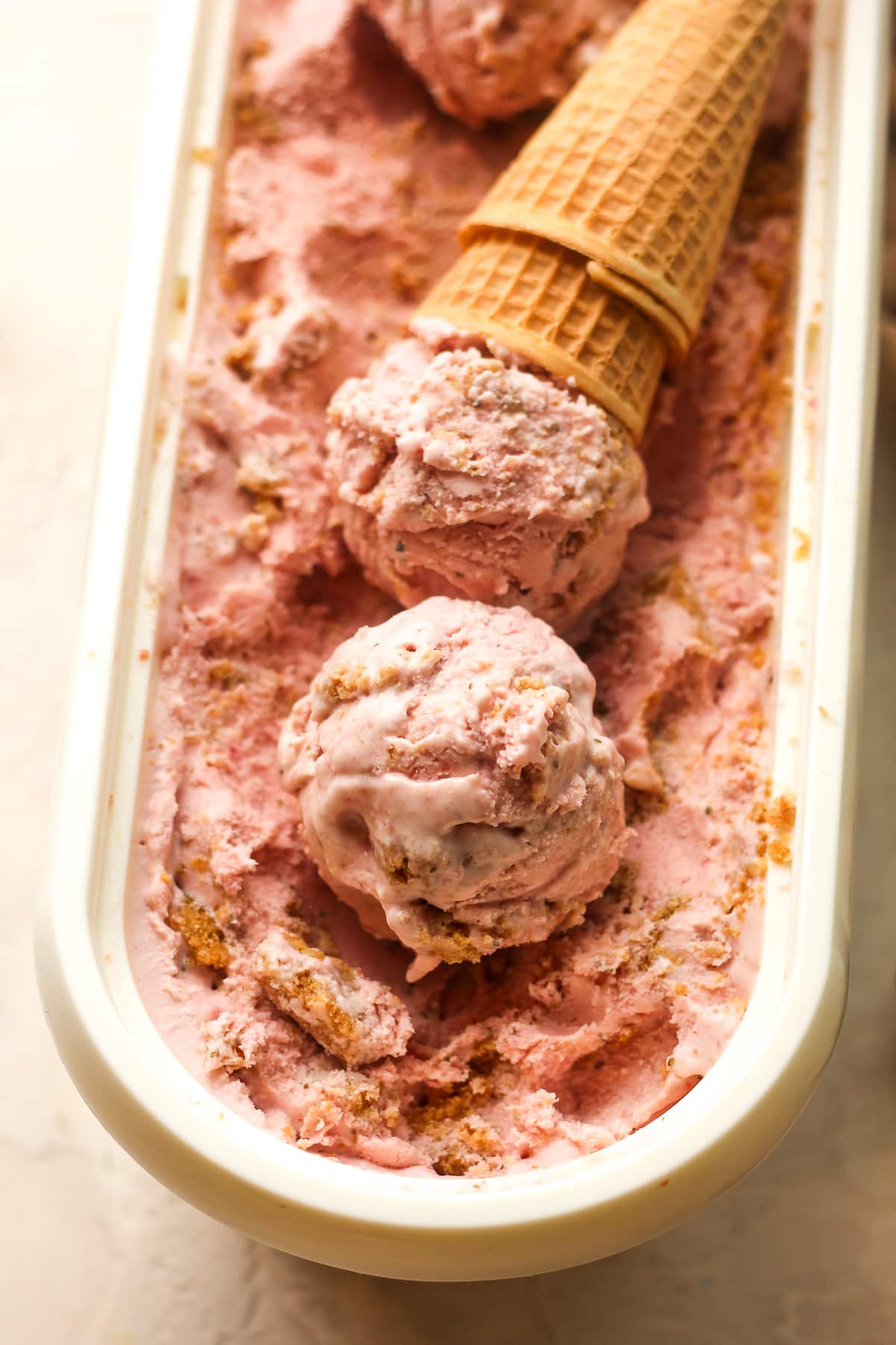A container of scoops of ice cream and two sugar cones.