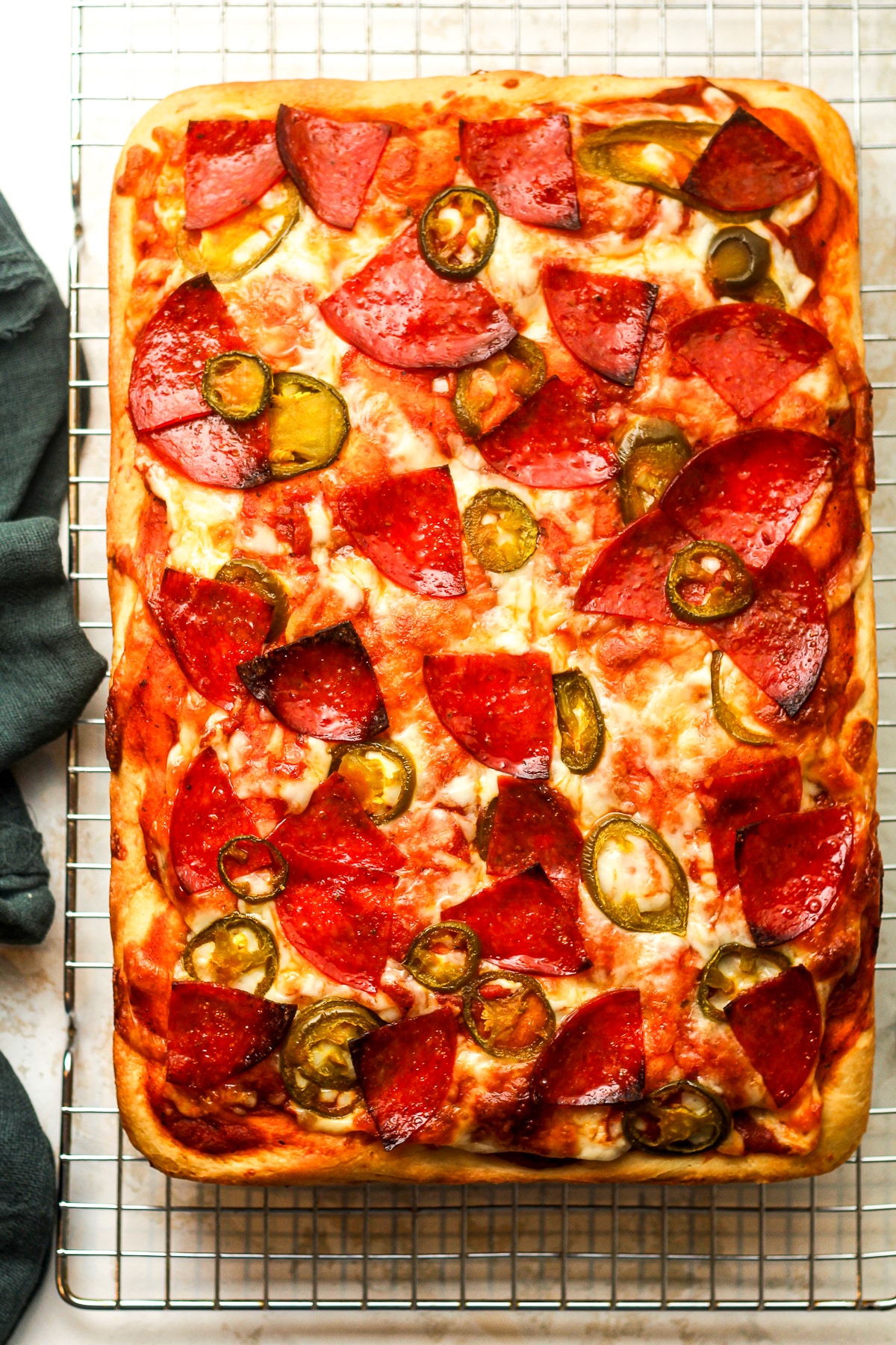 A large rectangle of focaccia pizza with pepperoni and jalapeños.