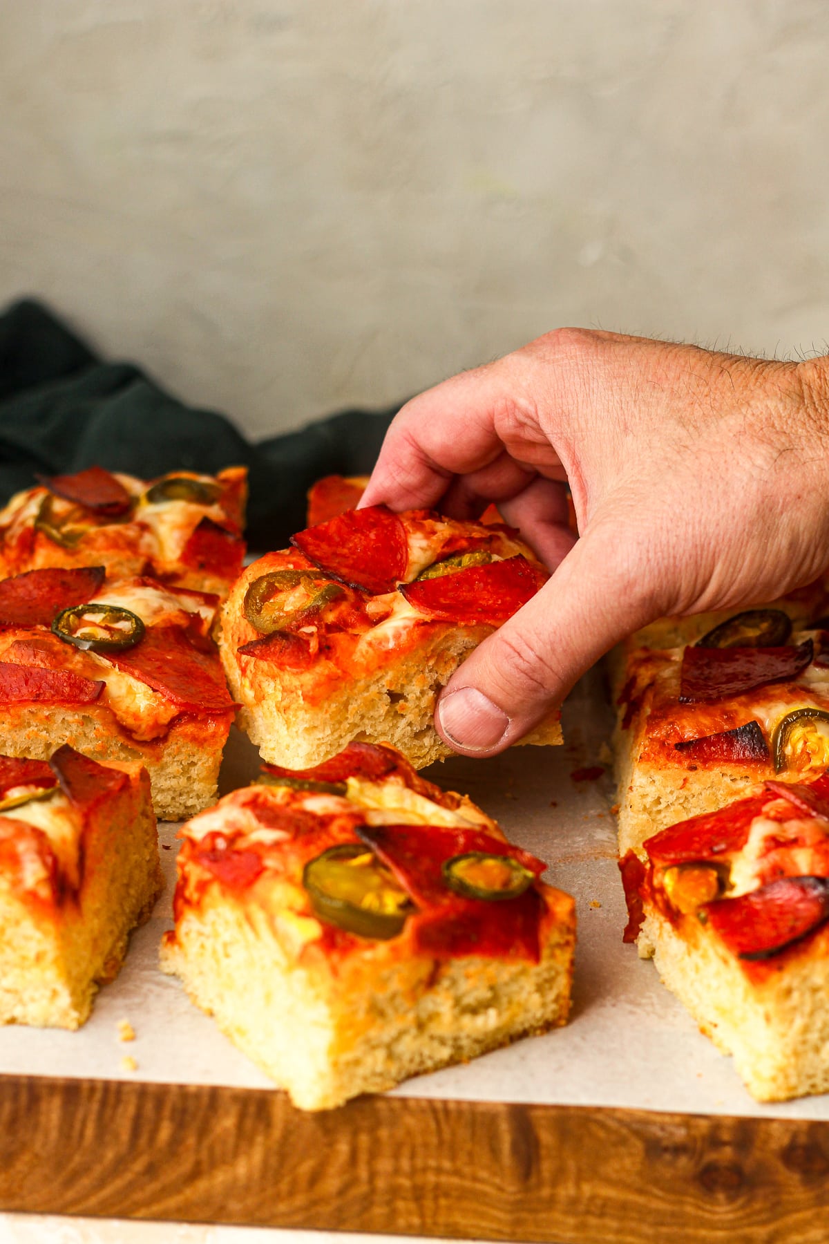 Side view of a hand reaching for a slice of pizza.