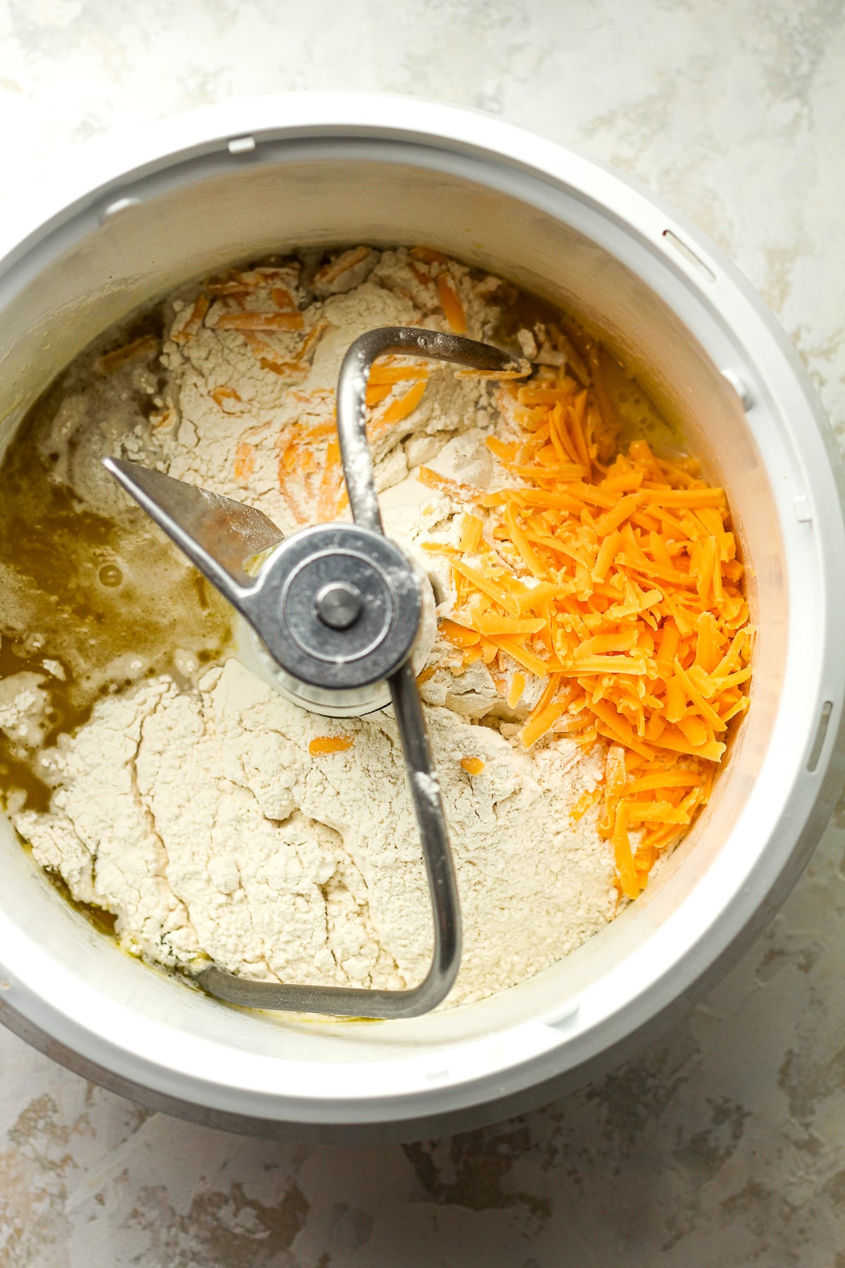 A mixer with the flour and cheddar on top.