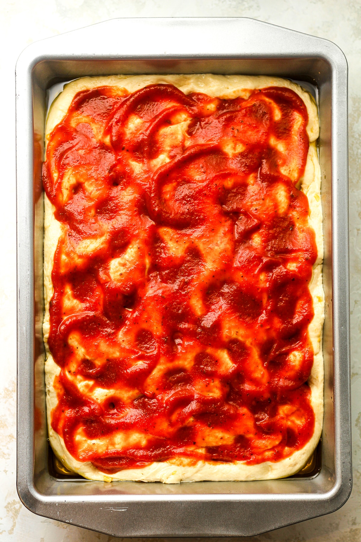 The focaccia dough with pizza sauce on top.