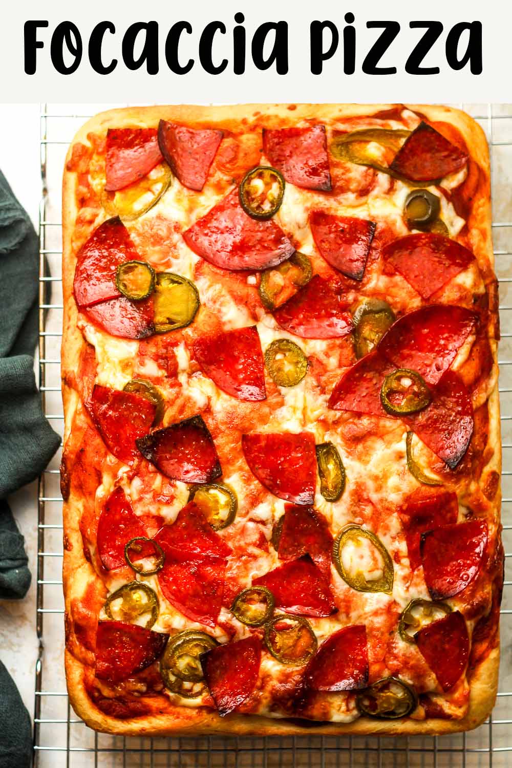 A large rectangular shot of a focaccia pizza with pepperoni and jalapeños.