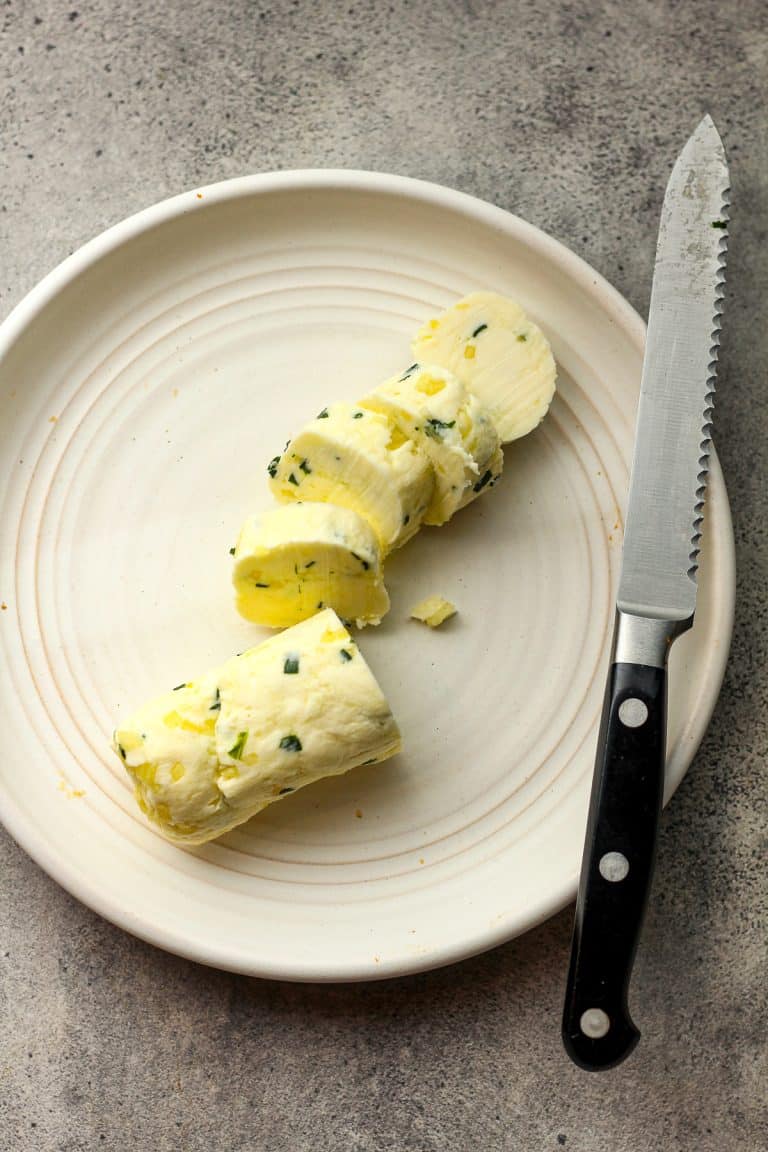 A plate of the sliced garlic butter with a knife.