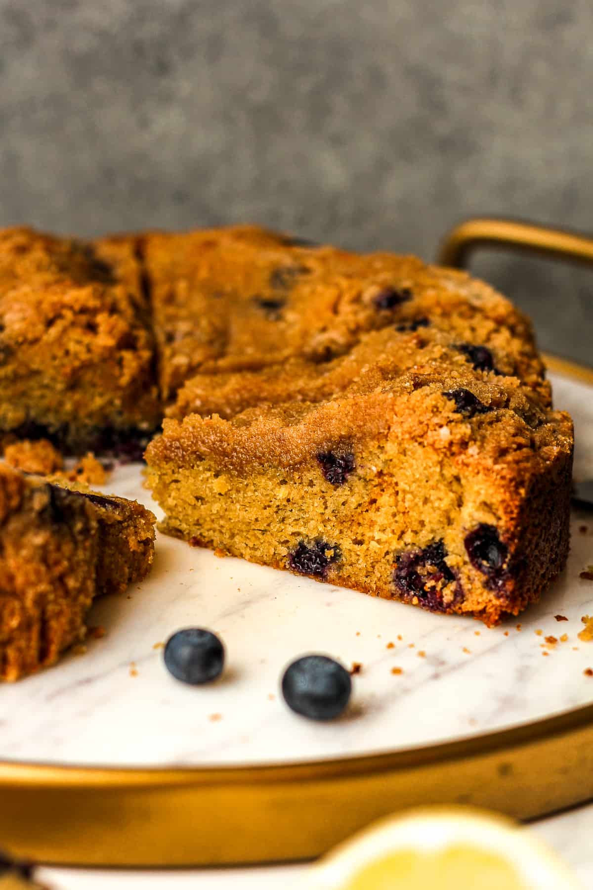 A side view of a platter of sliced coffee cake with blueberries.