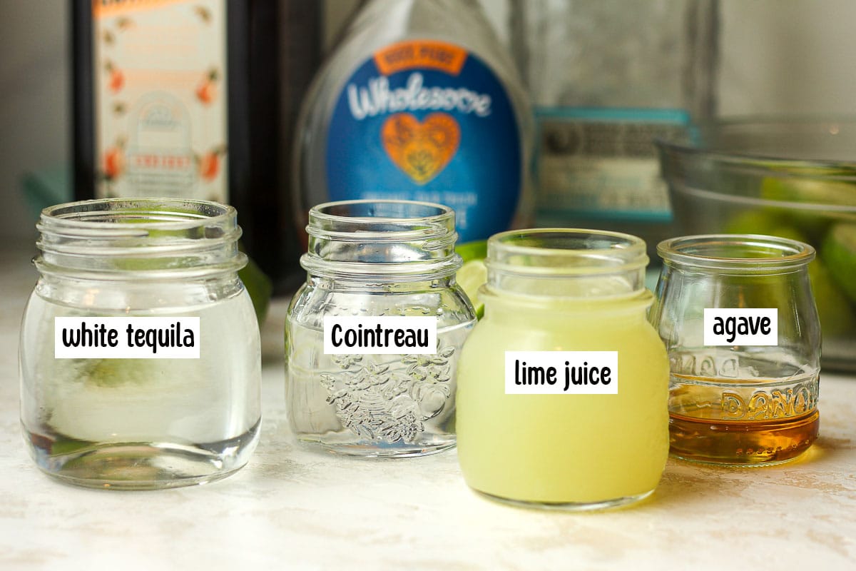Small jars of the ingredients for skinny margaritas with the bottles in the background.