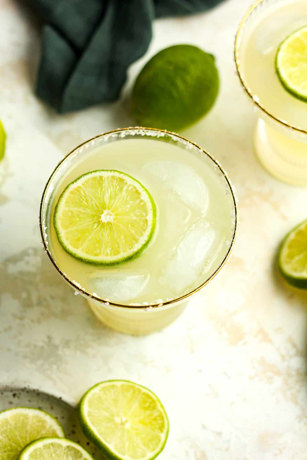 Overhead shot of two skinny margaritas with limes.