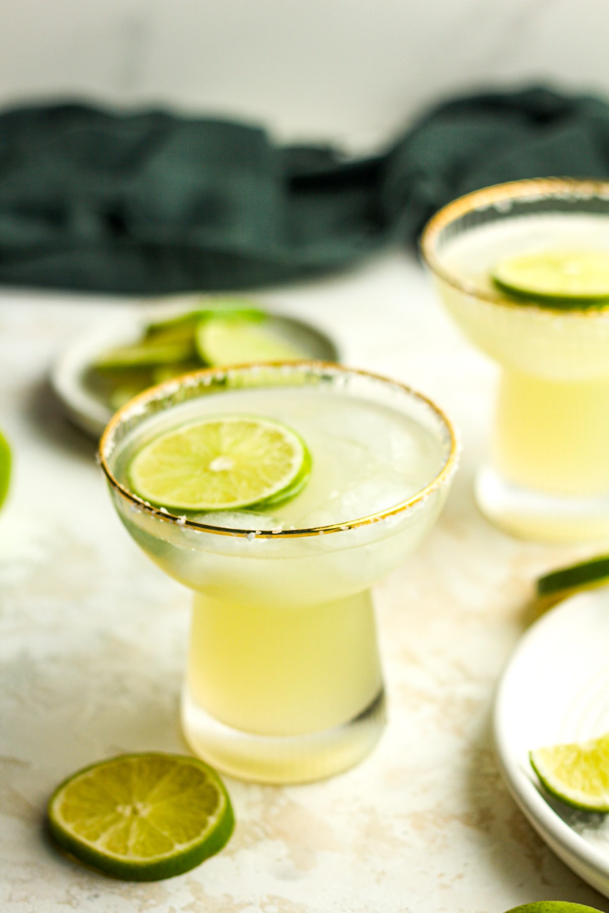 Side view of two skinny margaritas with lime slices.