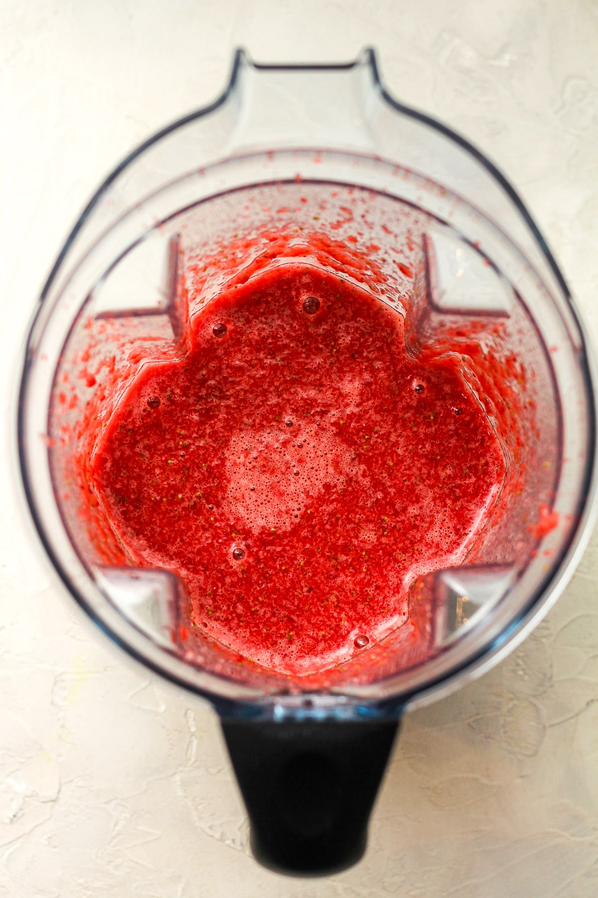 Overhead view of a mixer with pureed strawberries.