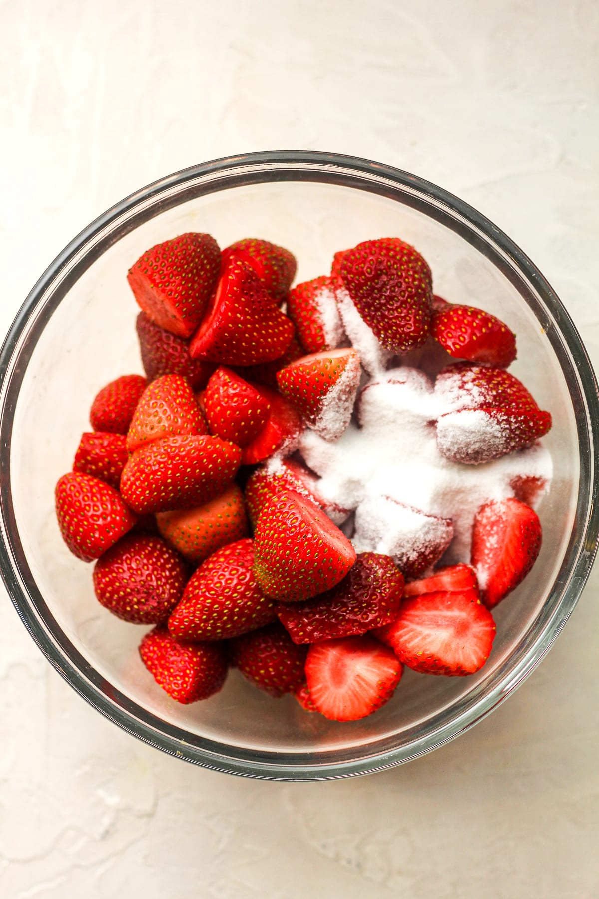 A bowl of strawberries and sugar.