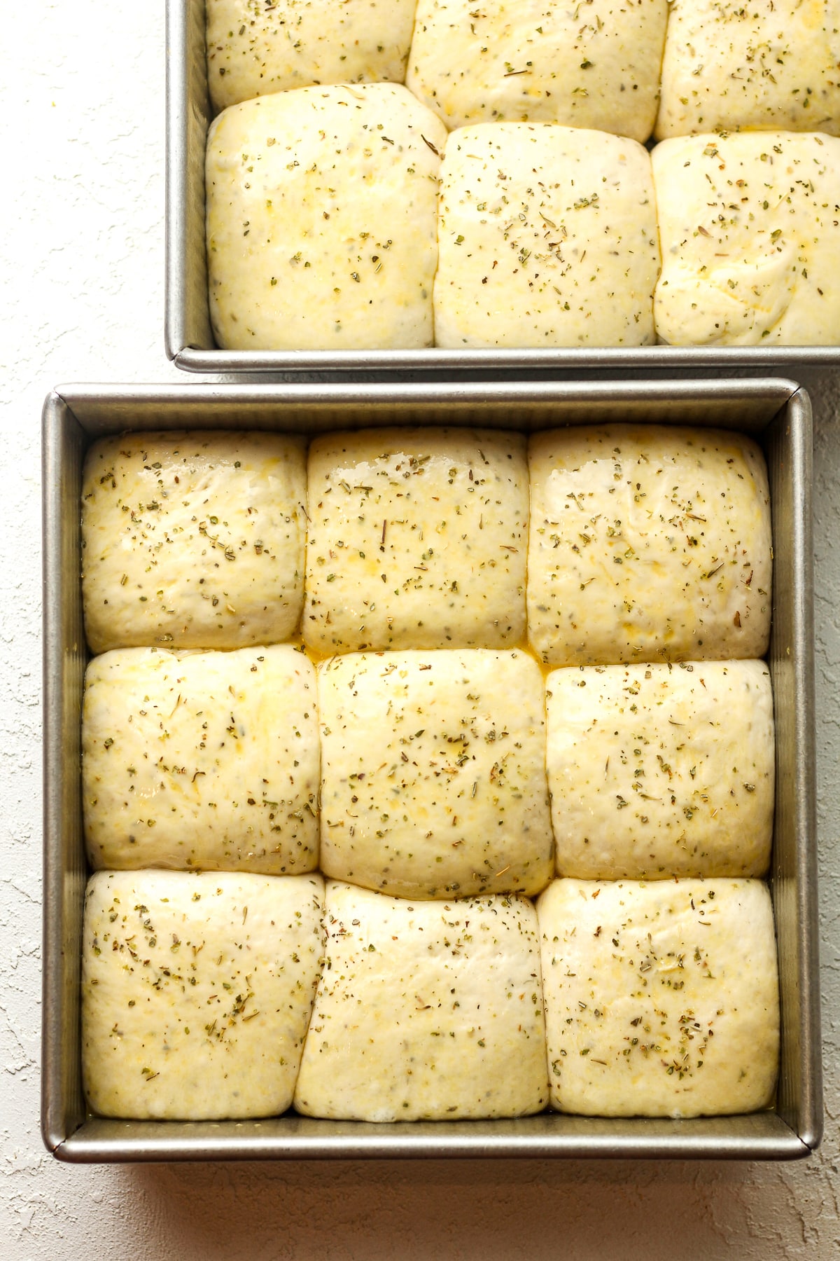 Two square pans of Italian dinner roll dough.