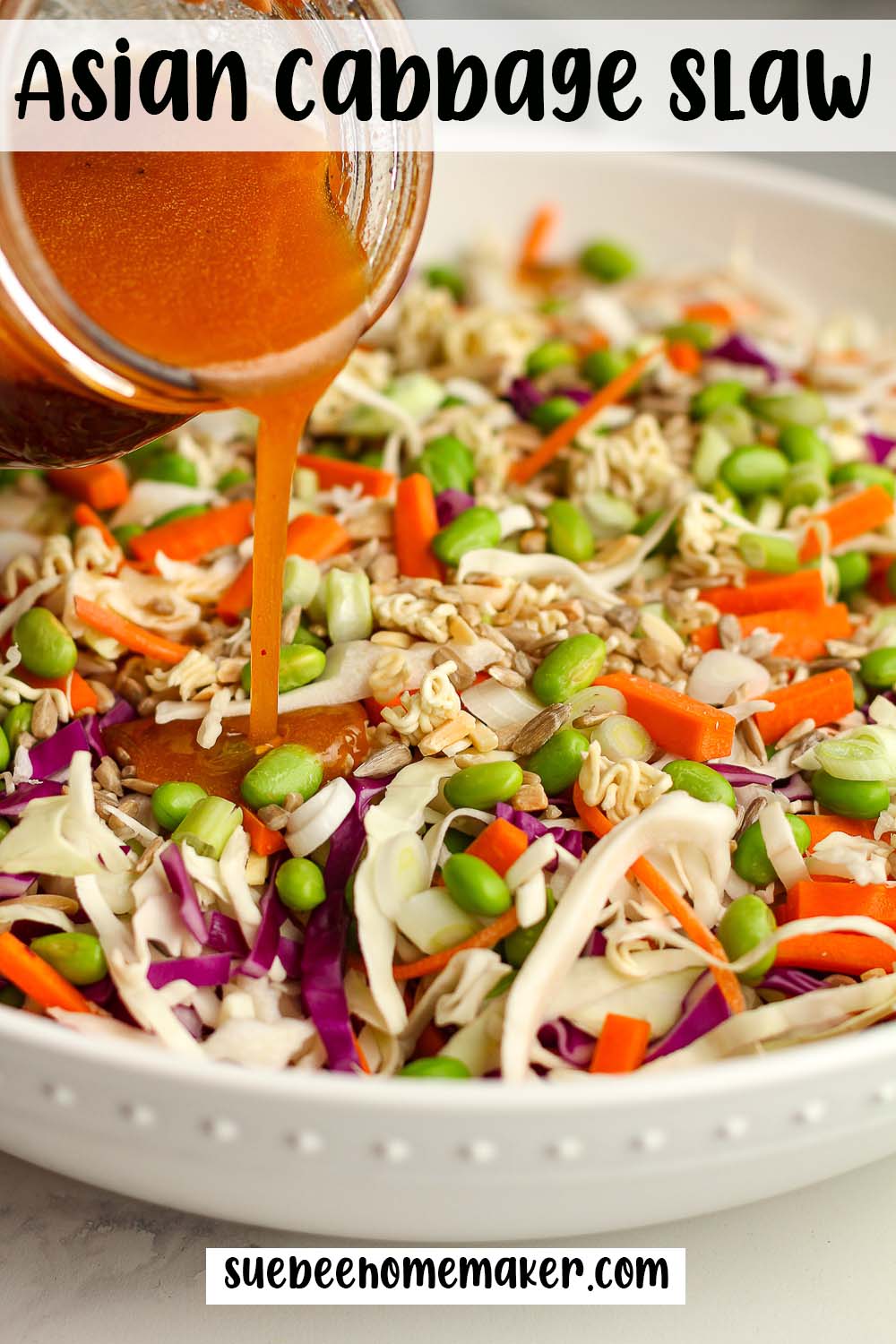 Side view of a bowl of Asian cabbage slaw with a jar of dressing pouring on top.
