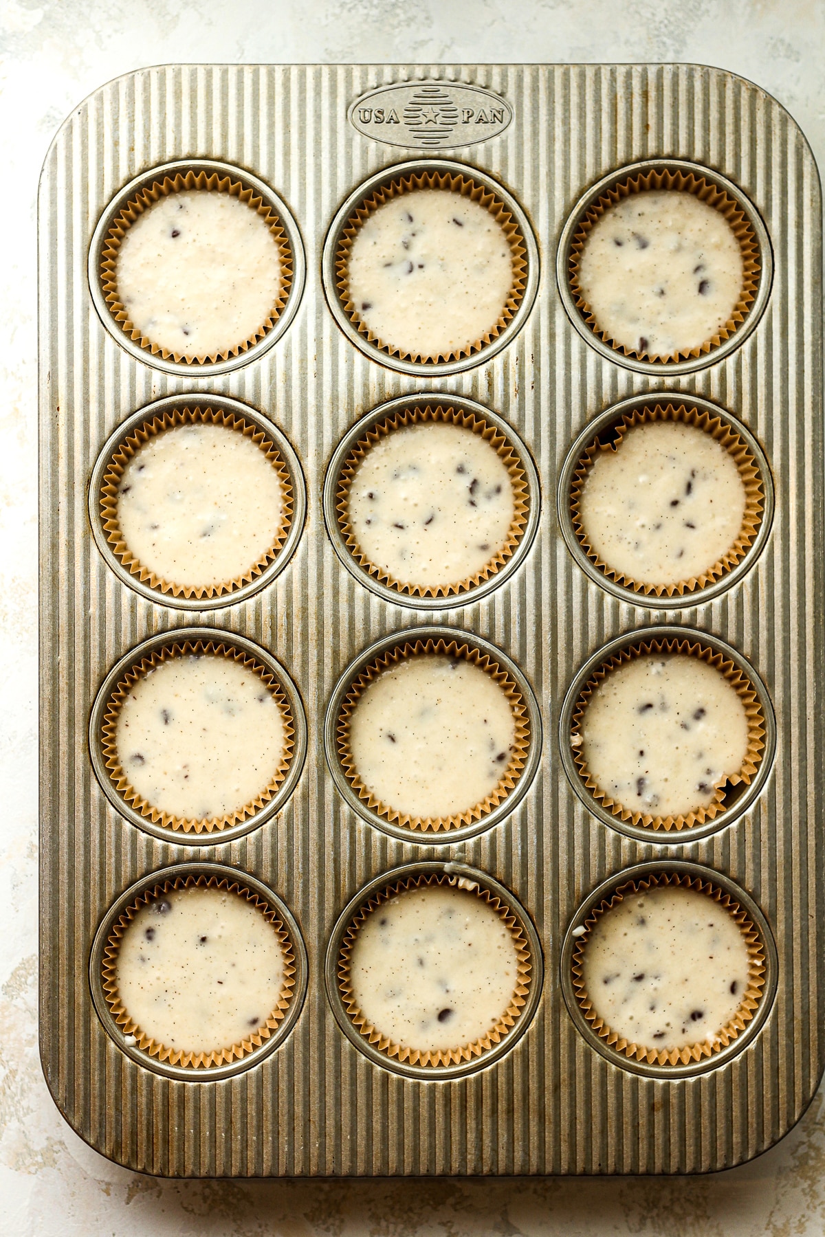 A muffin tin with liners filled with cupcake batter.