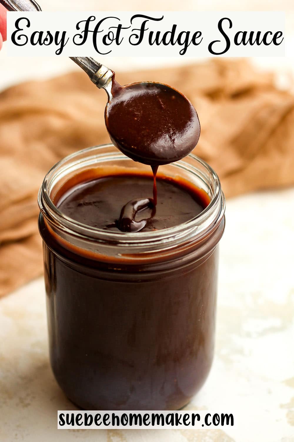 A jar of easy hot fudge sauce with a spoonful above the jar.