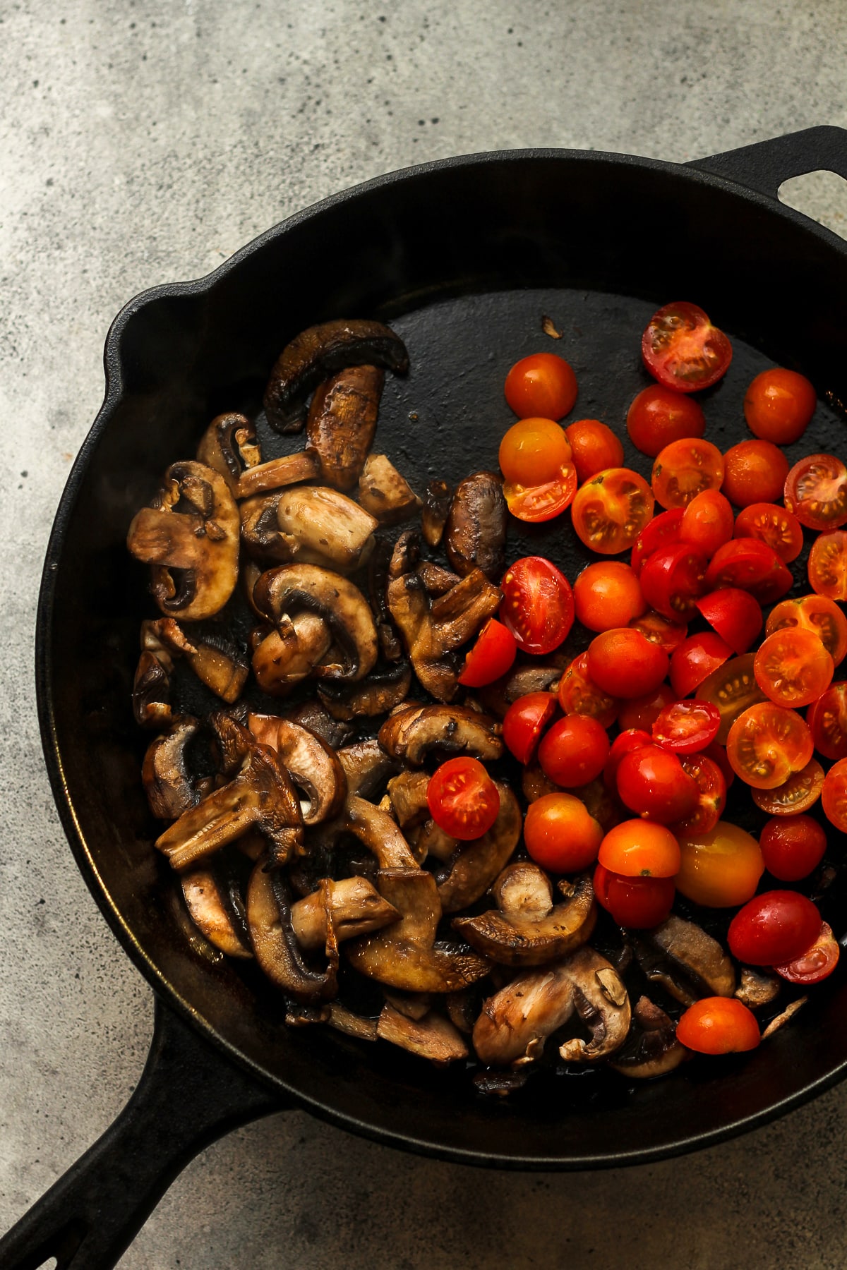 A skillet of the mushrooms and tomatoes.