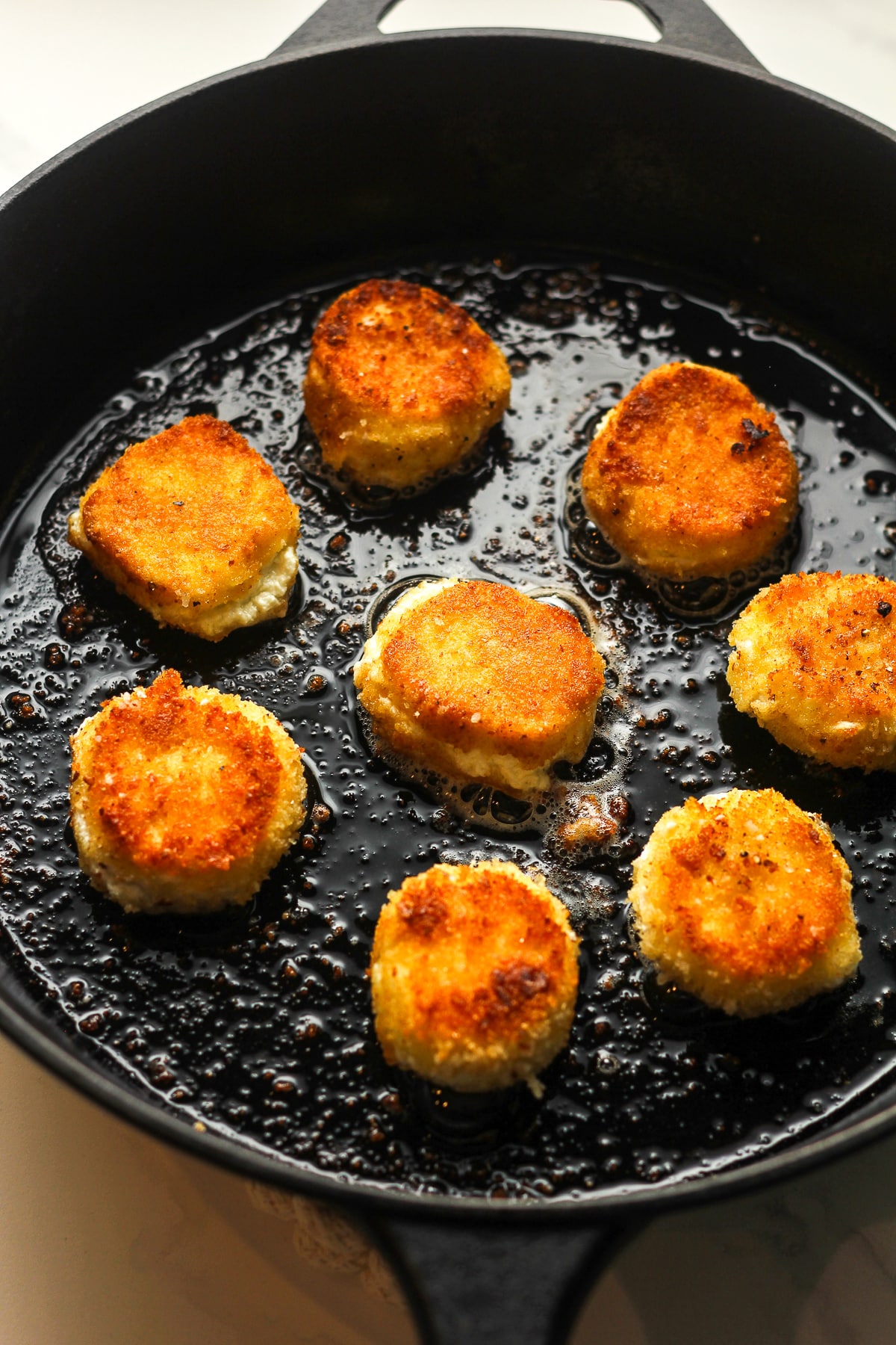A skillet of eight rounds of fried goat cheese.