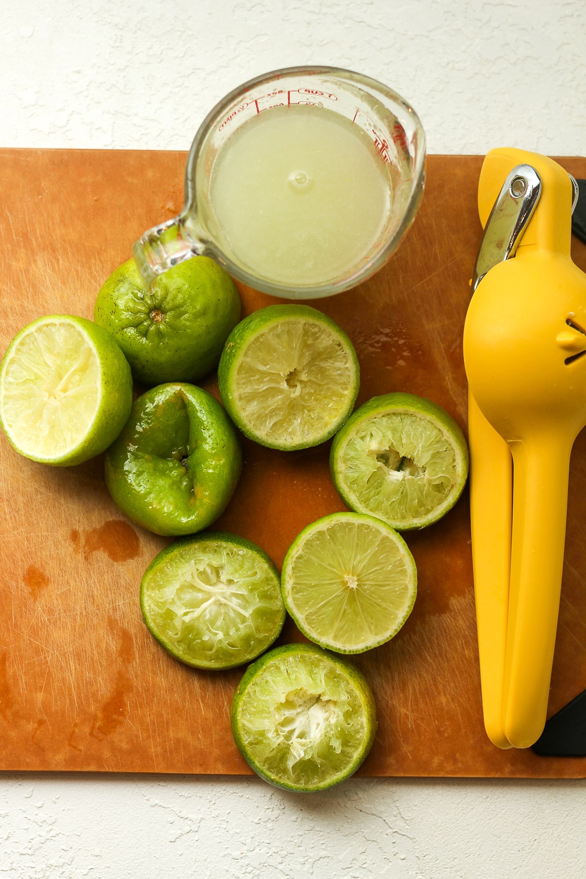 Overhead view of halved, squeezed limes with a cup of juice.