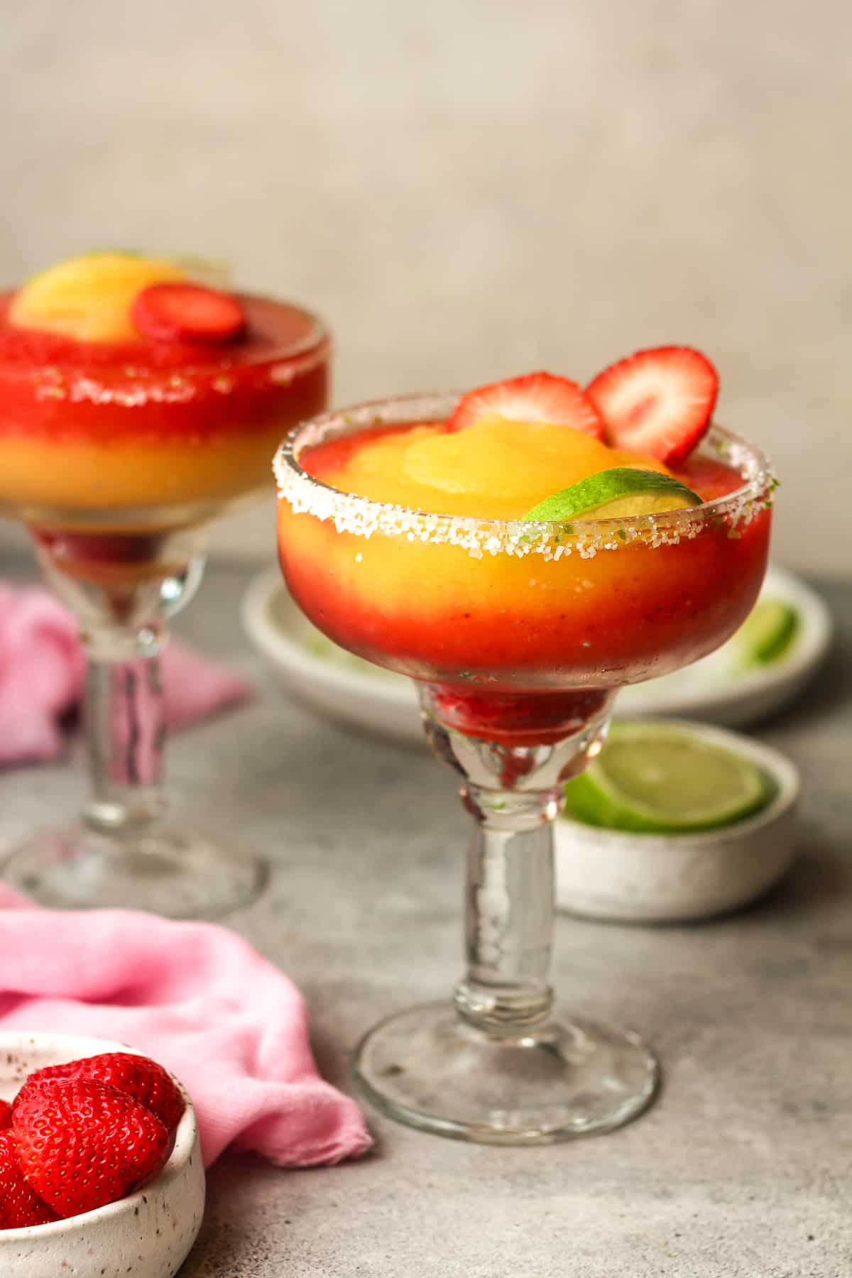 Side view of layered margaritas with lime wedges.