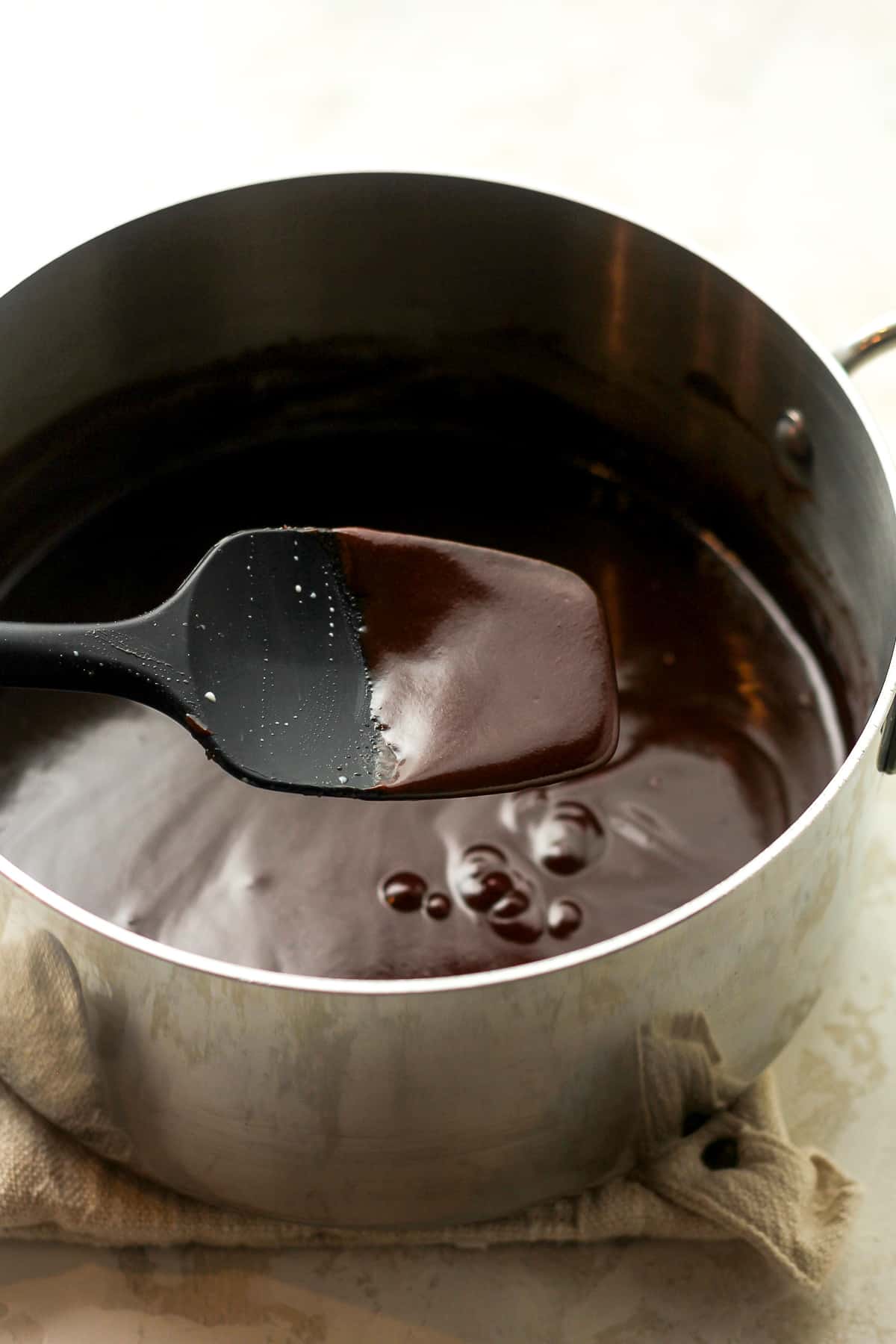 A pan of the hot fudge sauce with a spatula of sauce.