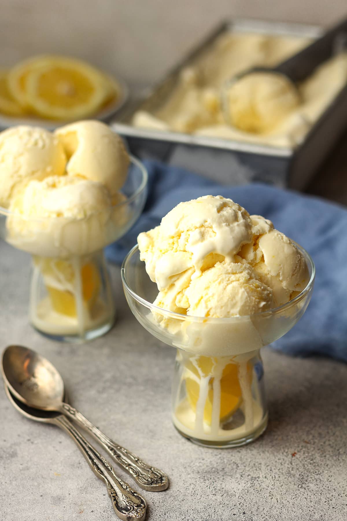 Overhead view of two bowls of lemon ice cream with spoons.