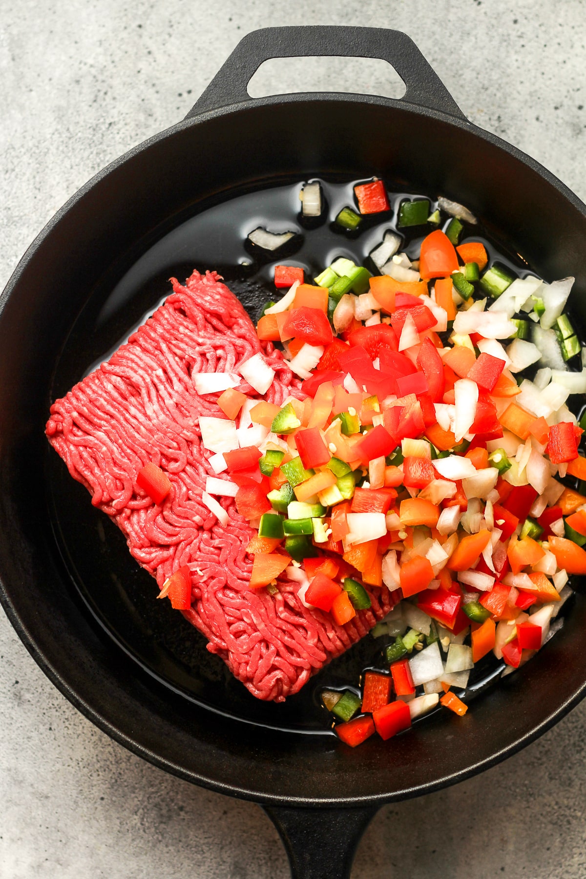 A skillet of diced veggies and ground beef.