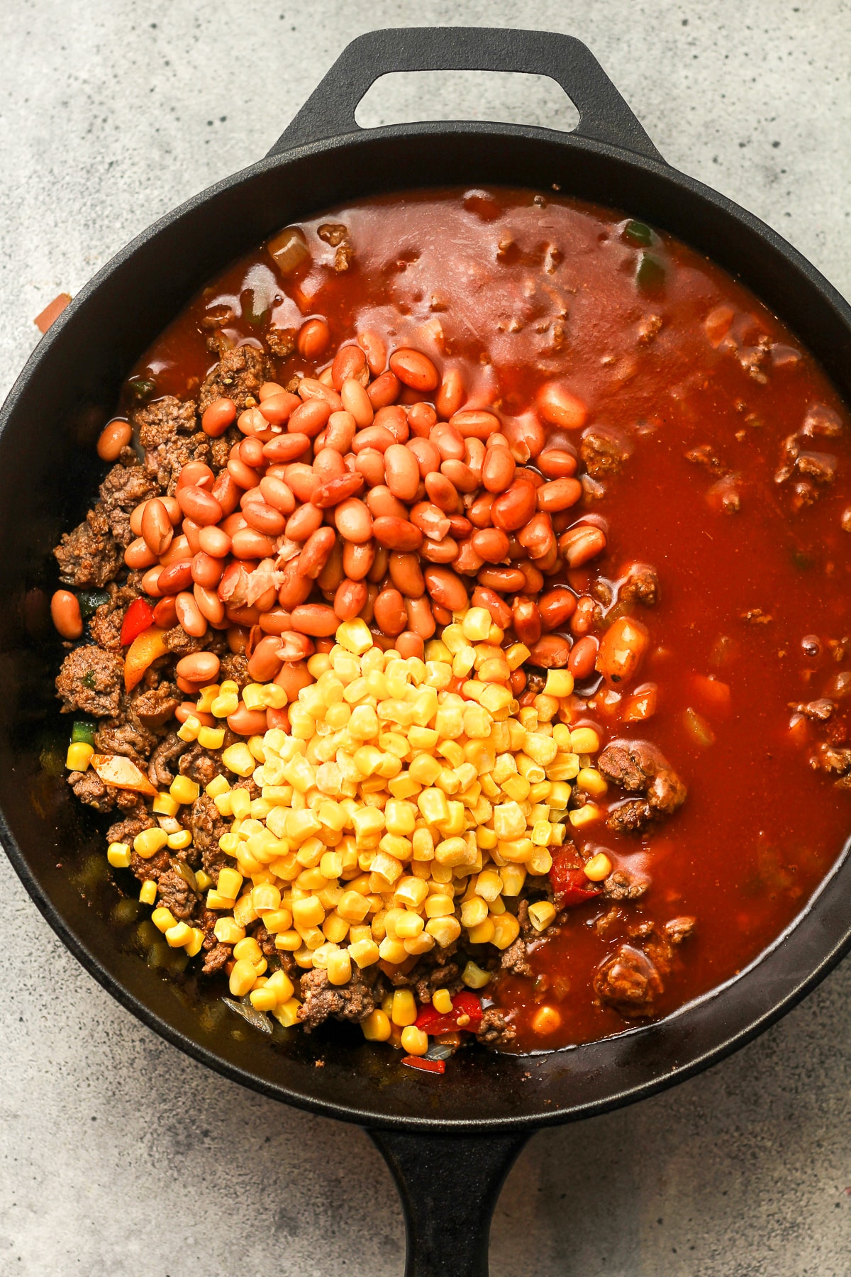 A skillet after adding the beans, corn, and enchilada sauce.