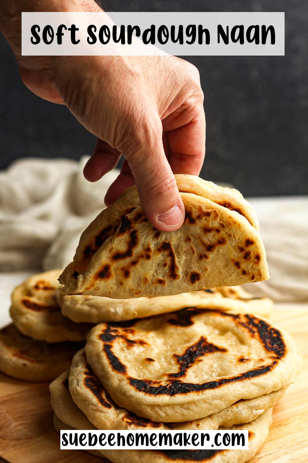A hand holding a rolled up soft sourdough naan.