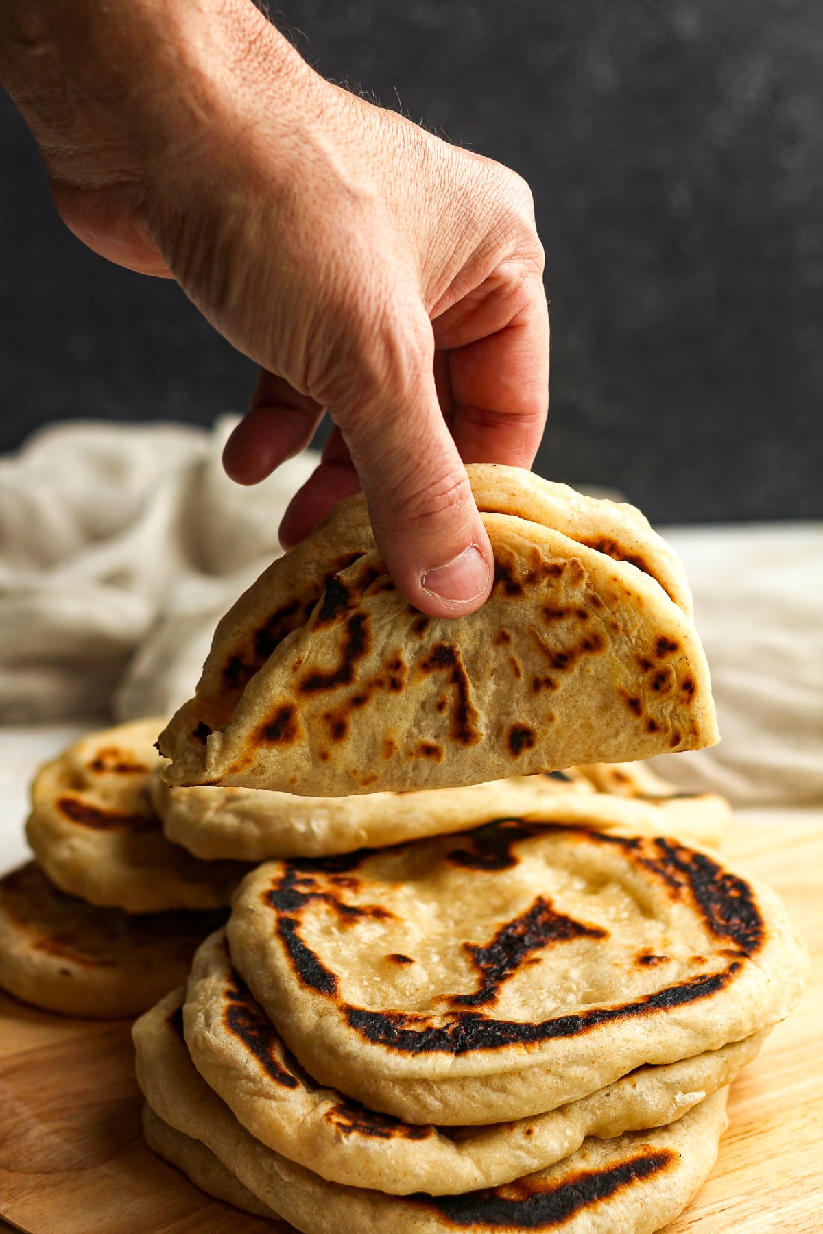 A hand holding a rolled up sourdough naan.