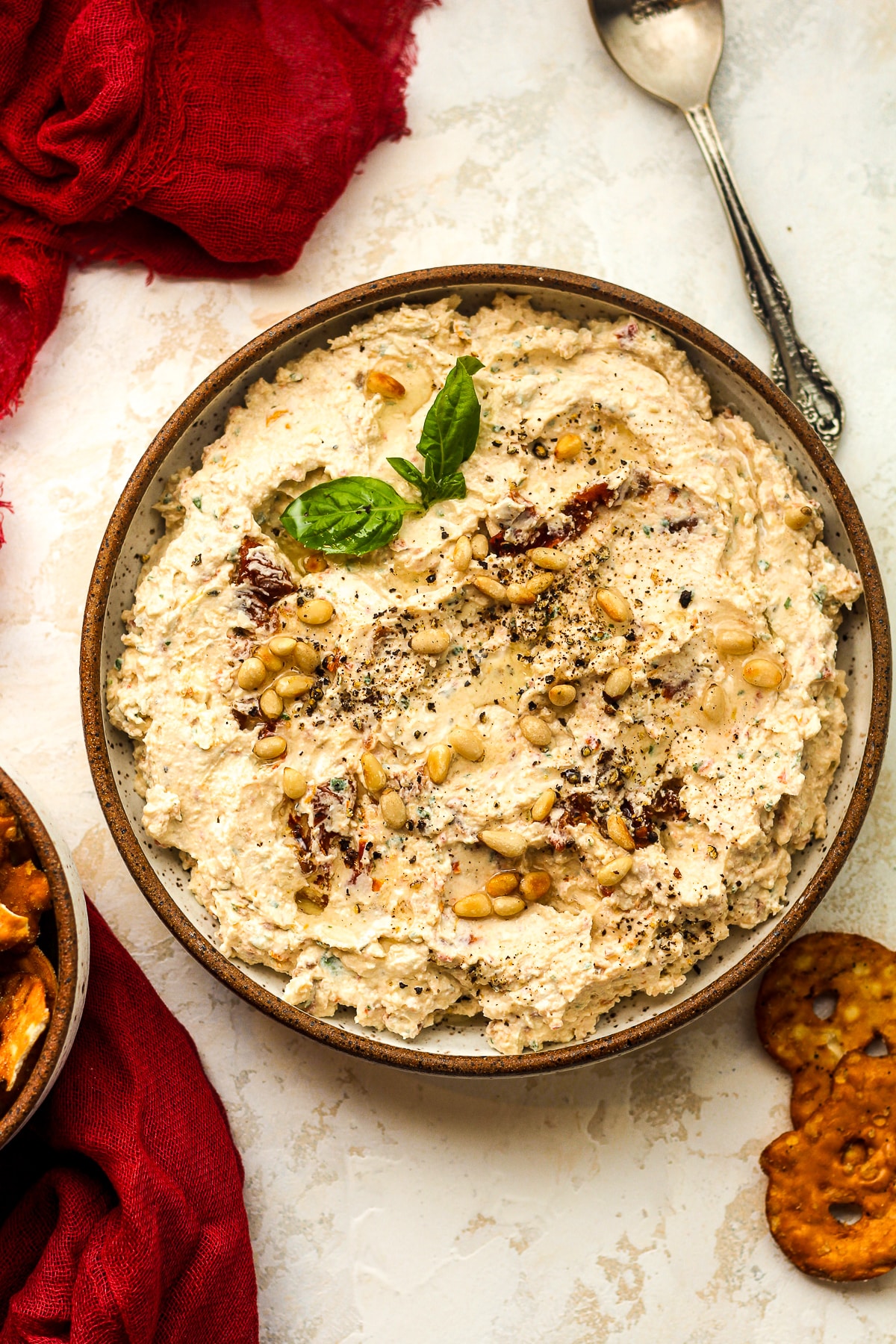 Overhead view of a bowl of cream cheese feta dip with sun-dried tomatoes.