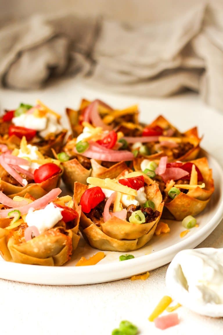 Side view of a plate of taco wonton cups with crispy edges.