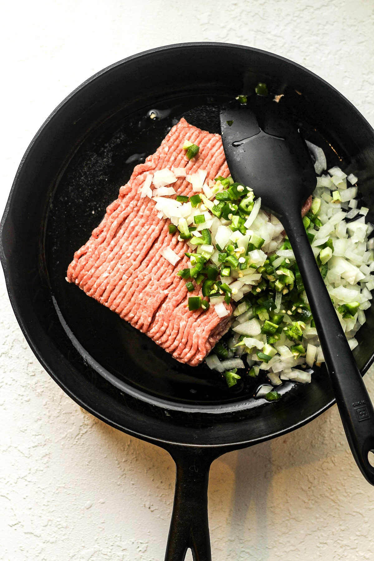 A skillet of the raw meat plus diced veggies.