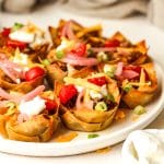 Side view of a plate of taco wonton cups with toppings.