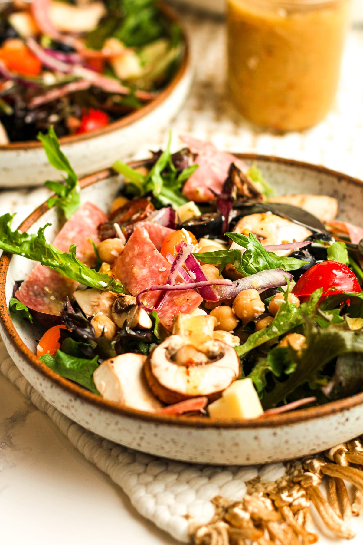 Side view of two bowls of antipasto salad with the dressing.