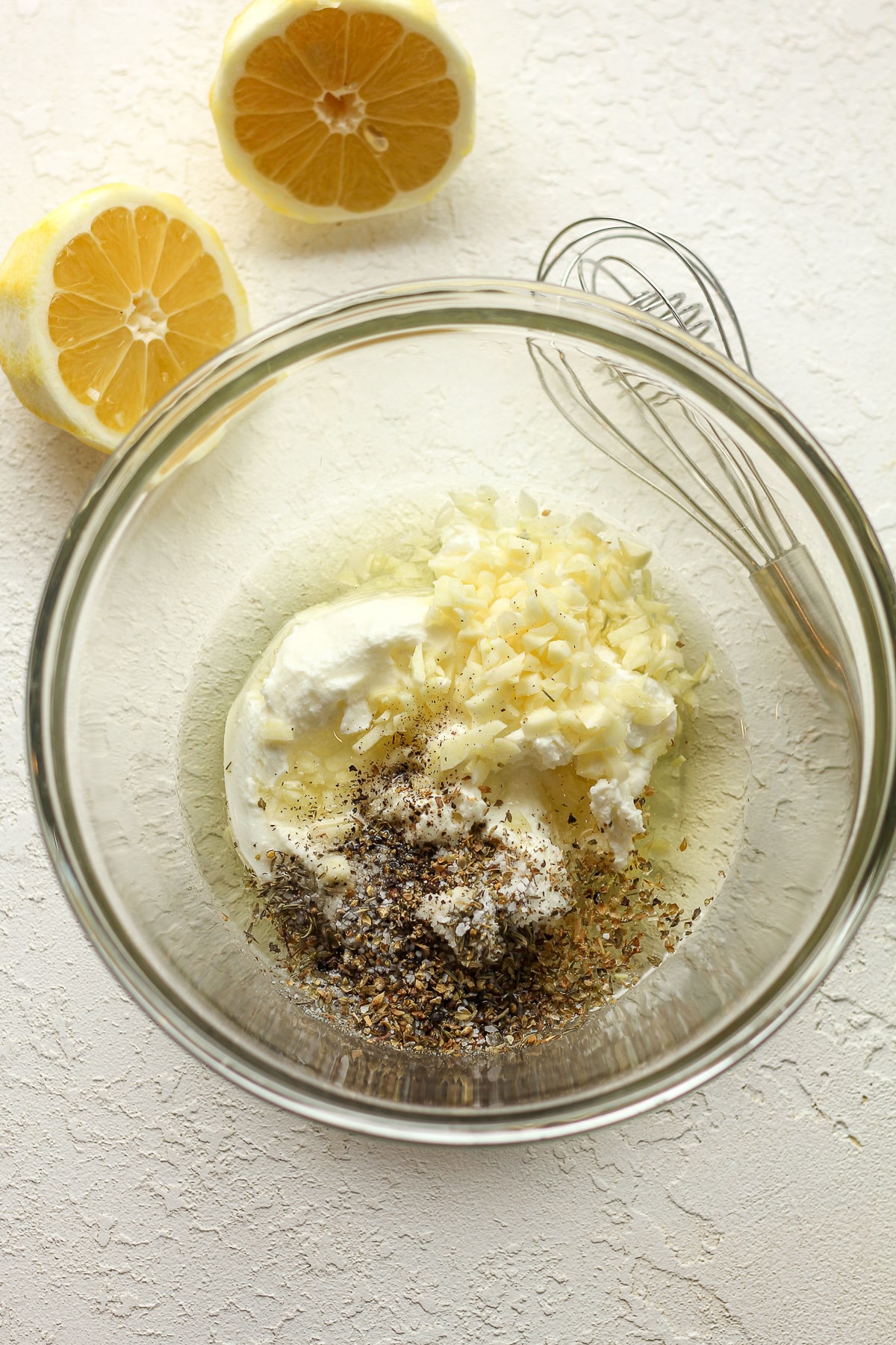 A bowl of the yogurt marinade with lemon halves next to the bowl.