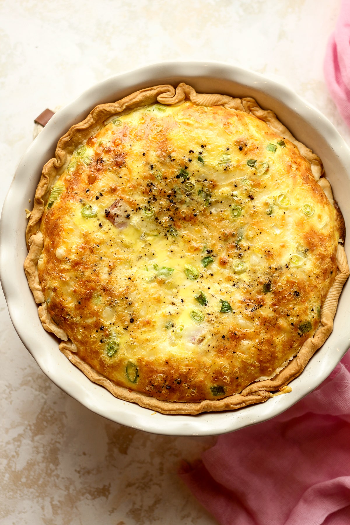 A baked ham and gruyere quiche in a pie plate.