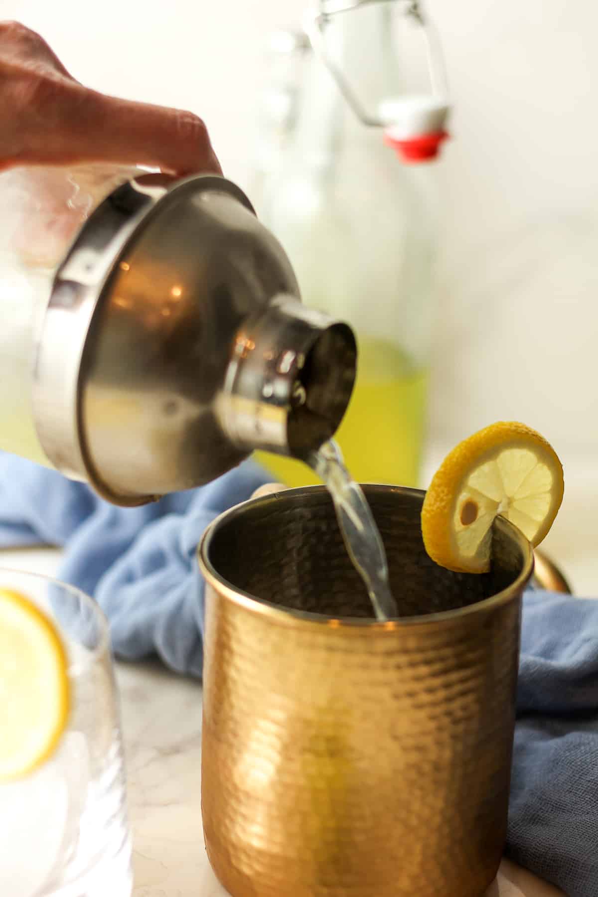 Side view of a cocktail shaker pouring limoncello mules.