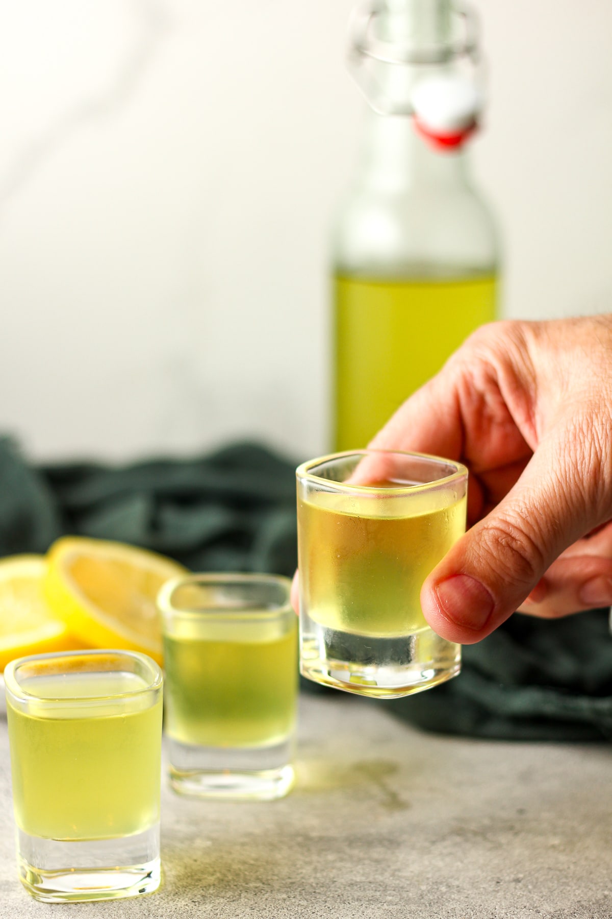 A hand holding up a shot of homemade limoncello.