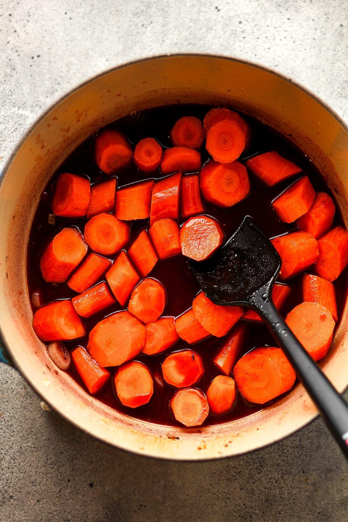 A pot with the wine mixture and carrots.