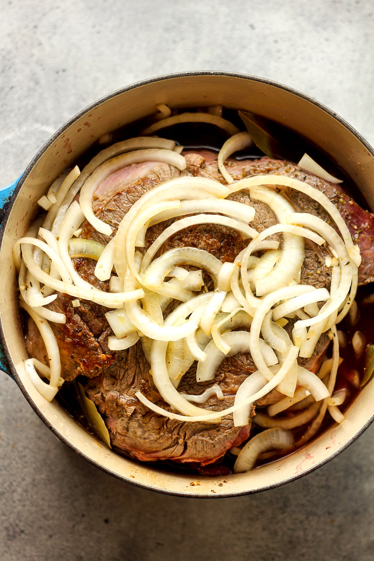 A pot of the browned roast with onions on top.