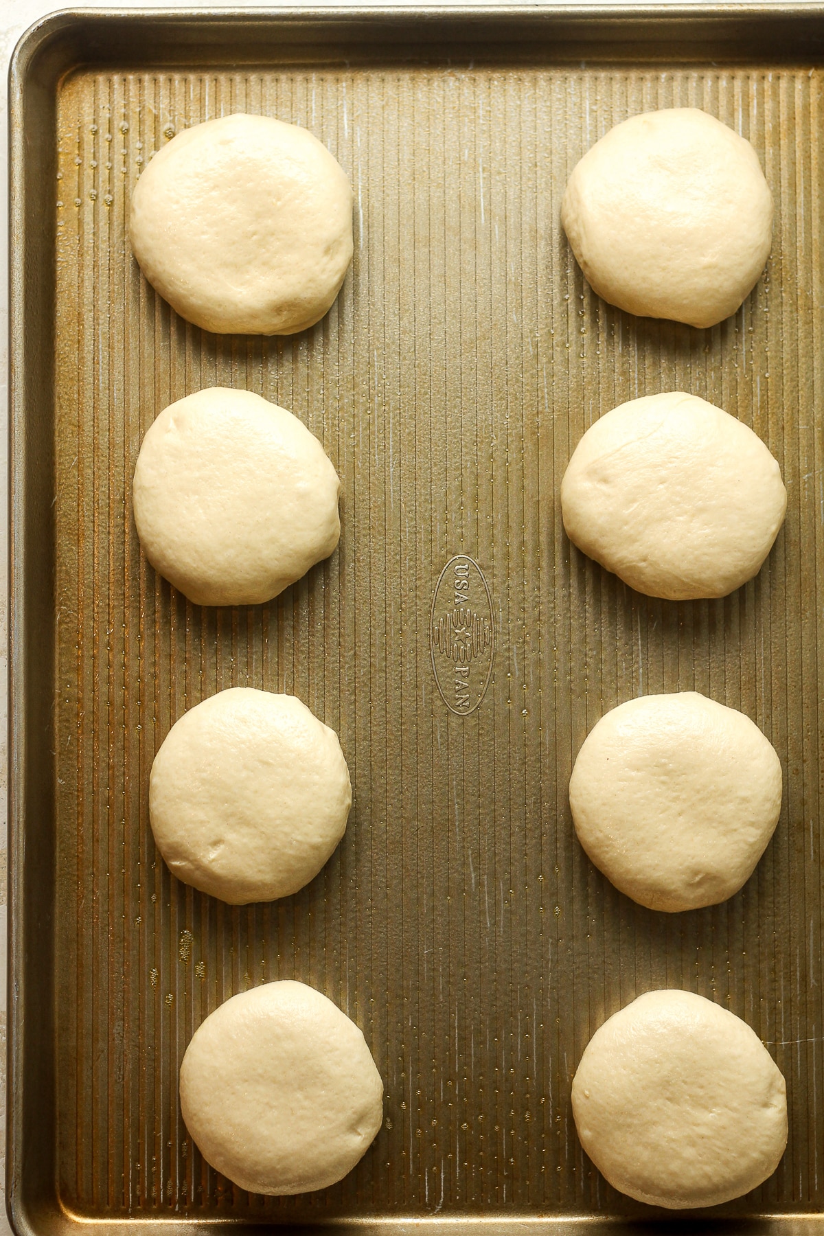 Eight dough rounds on a baking sheet.